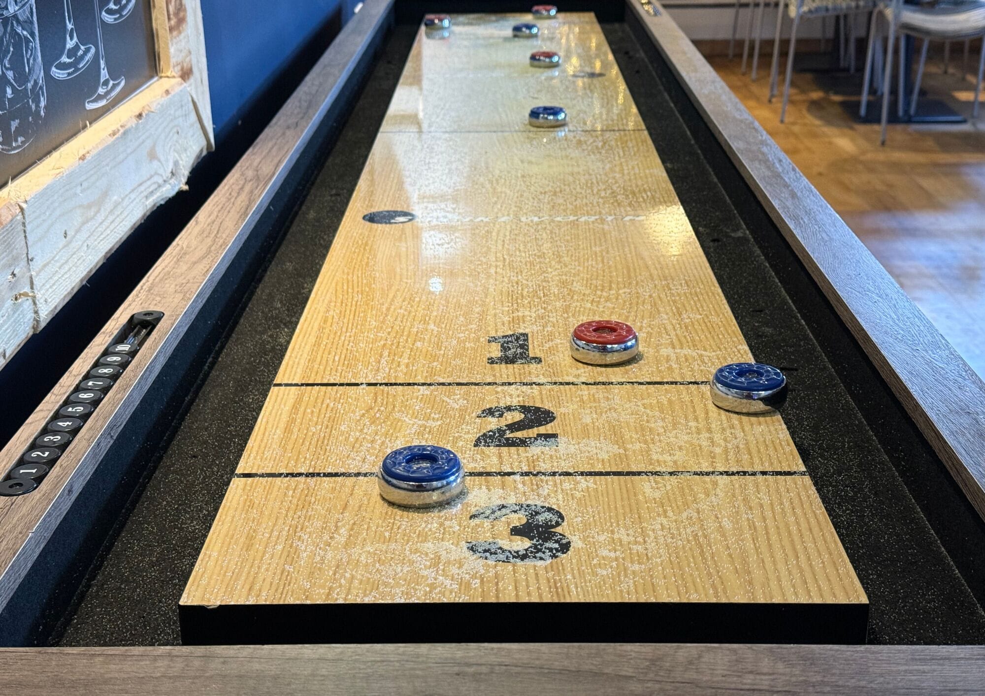 A shuffleboard table with numbered scoring areas and pucks.