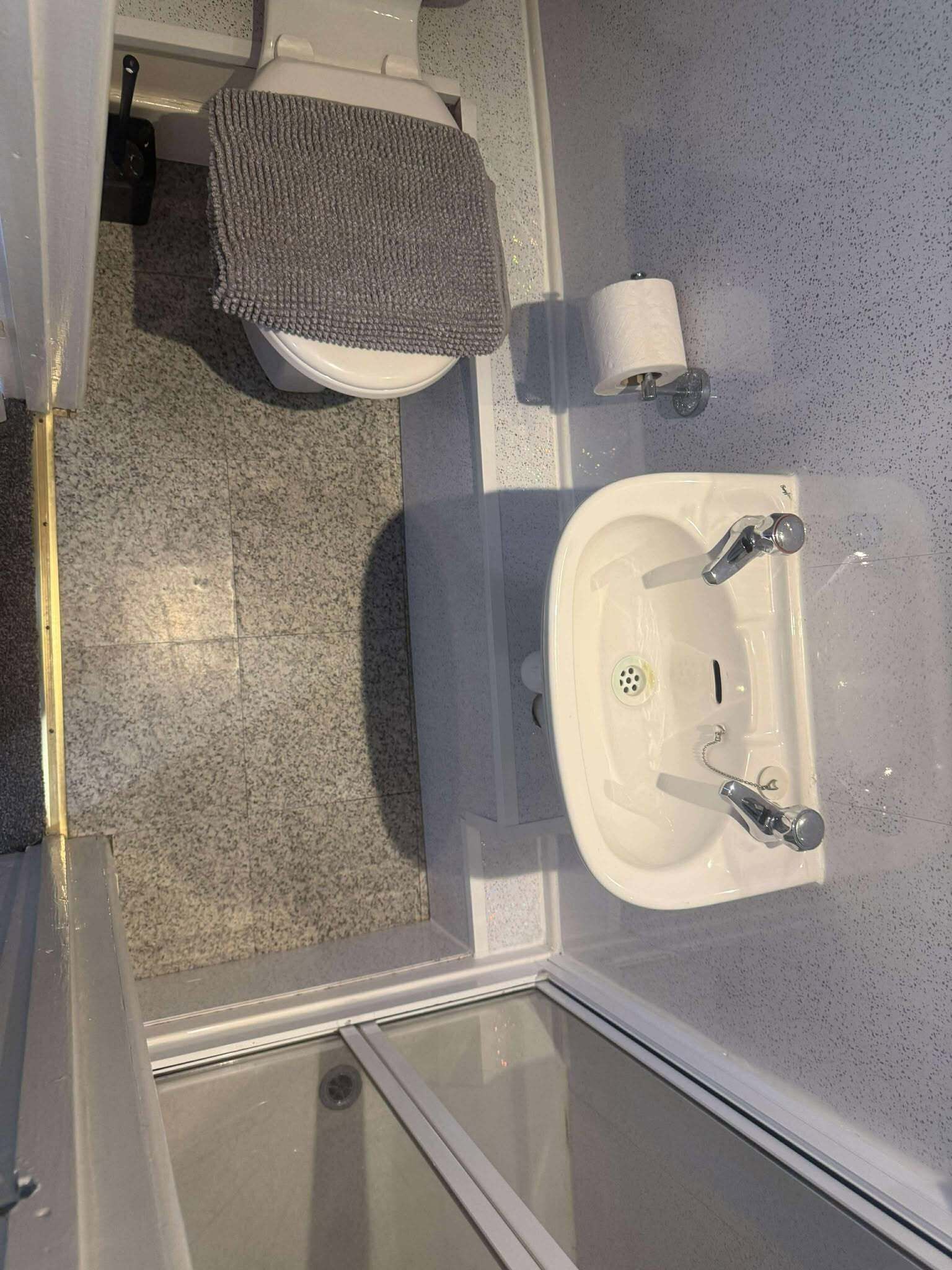 Baño con inodoro, lavamanos y zona de ducha.