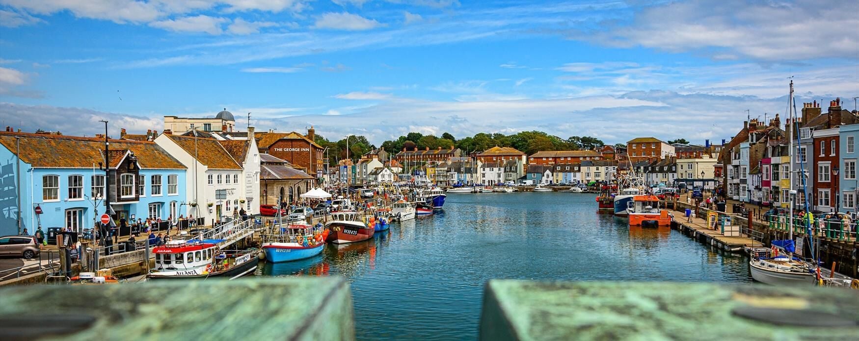 A harbor with boats docked, buildings along the waterfront, and a clear sky.