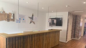 Una zona de recepción con un mostrador de madera, un adorno de estrella colgada y un cartel en la pared con indicaciones.