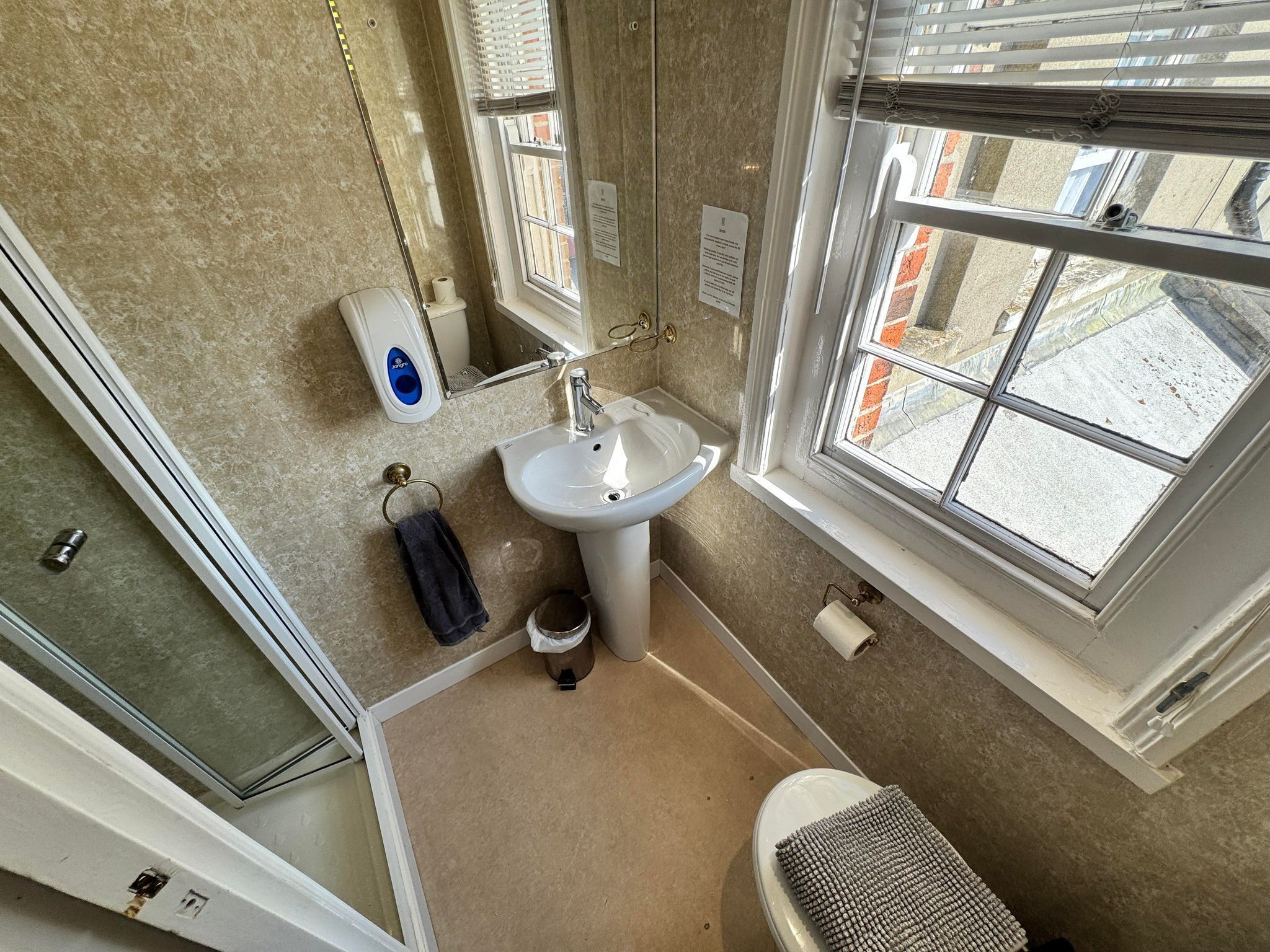 A bathroom with a toilet, sink, and window.
