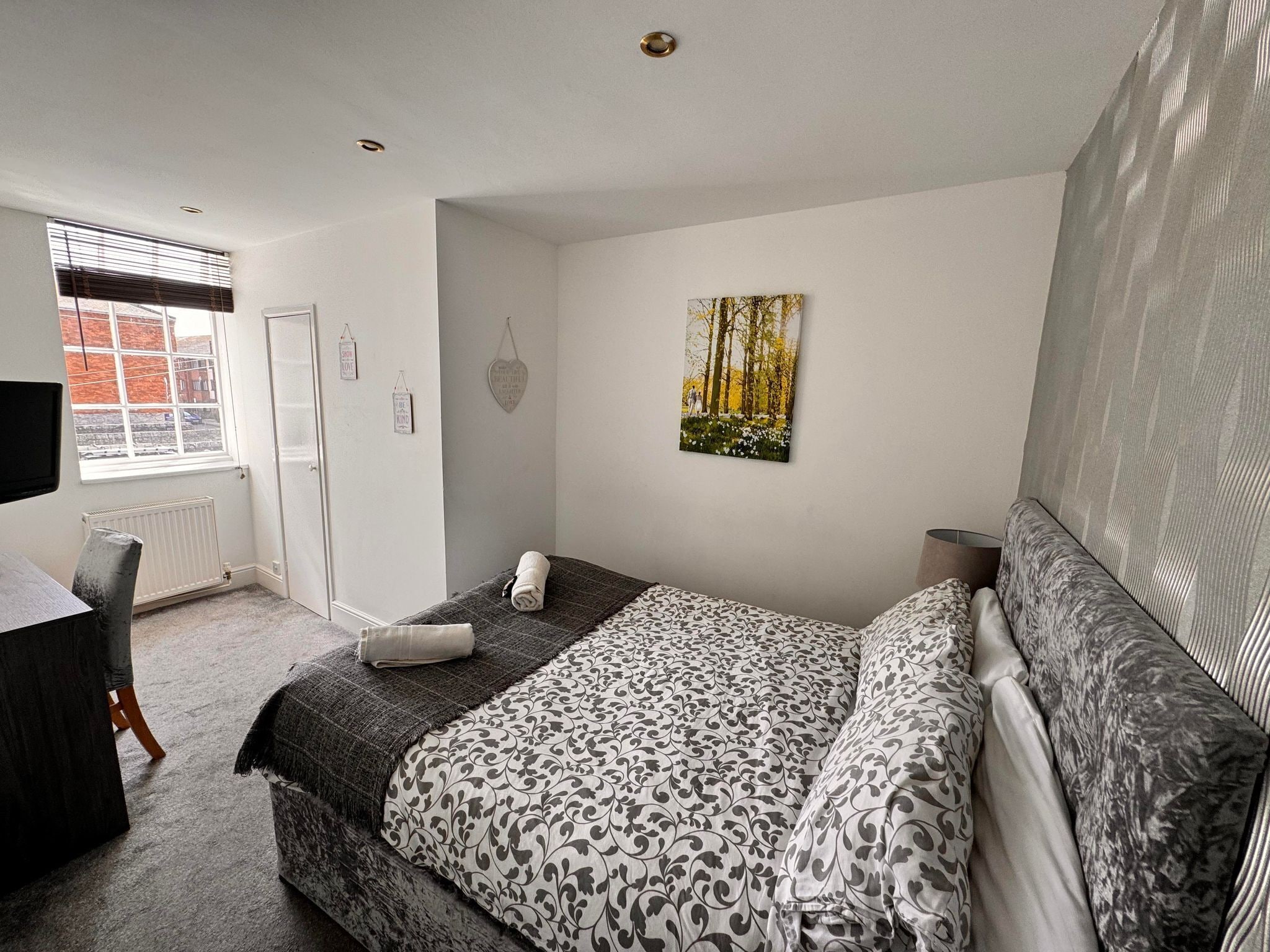 A bedroom with a bed, a desk, and a window.