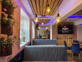 Interior de restaurante con cabinas, lámparas colgantes y pared de ladrillo con un letrero.