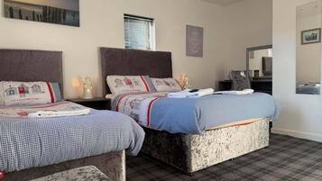 Una habitación de hotel con dos camas, un ventanal grande, un cuadro en la pared y un espejo.