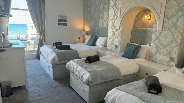 Habitación de hotel con dos camas, un escritorio y vista al mar.