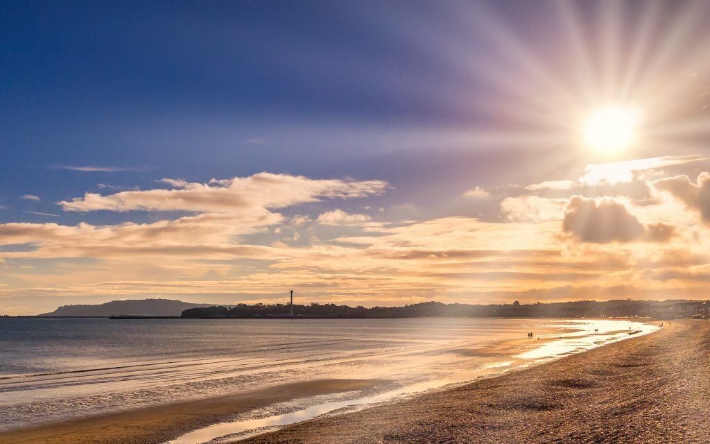 A beach with a clear sky and the sun setting or rising.