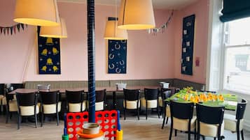 A restaurant interior with multiple tables, chairs, hanging lamps, and a wall with a menu board.