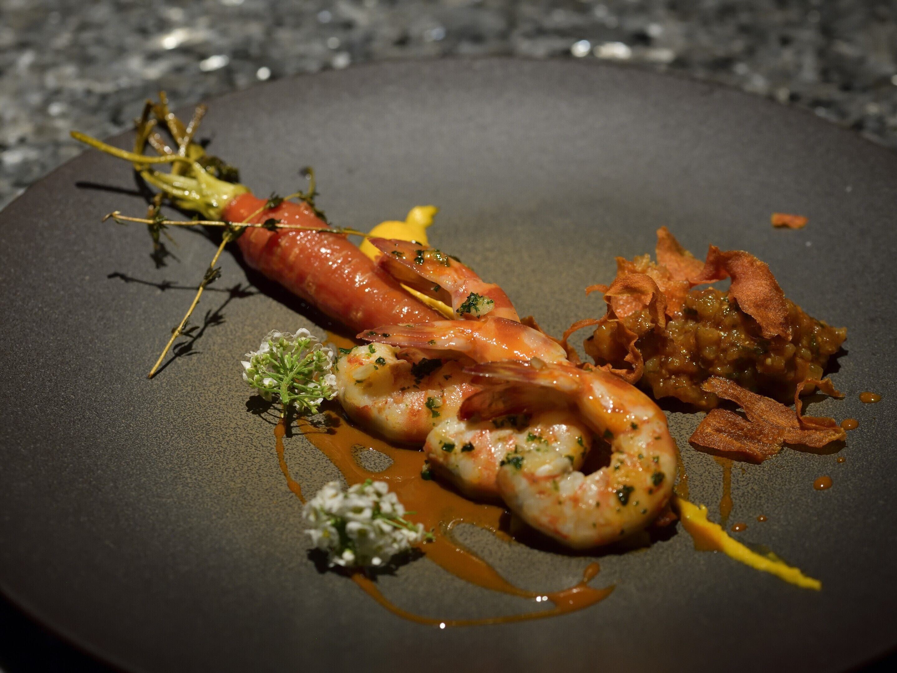 A plate of food with shrimp, a carrot, and a side dish.