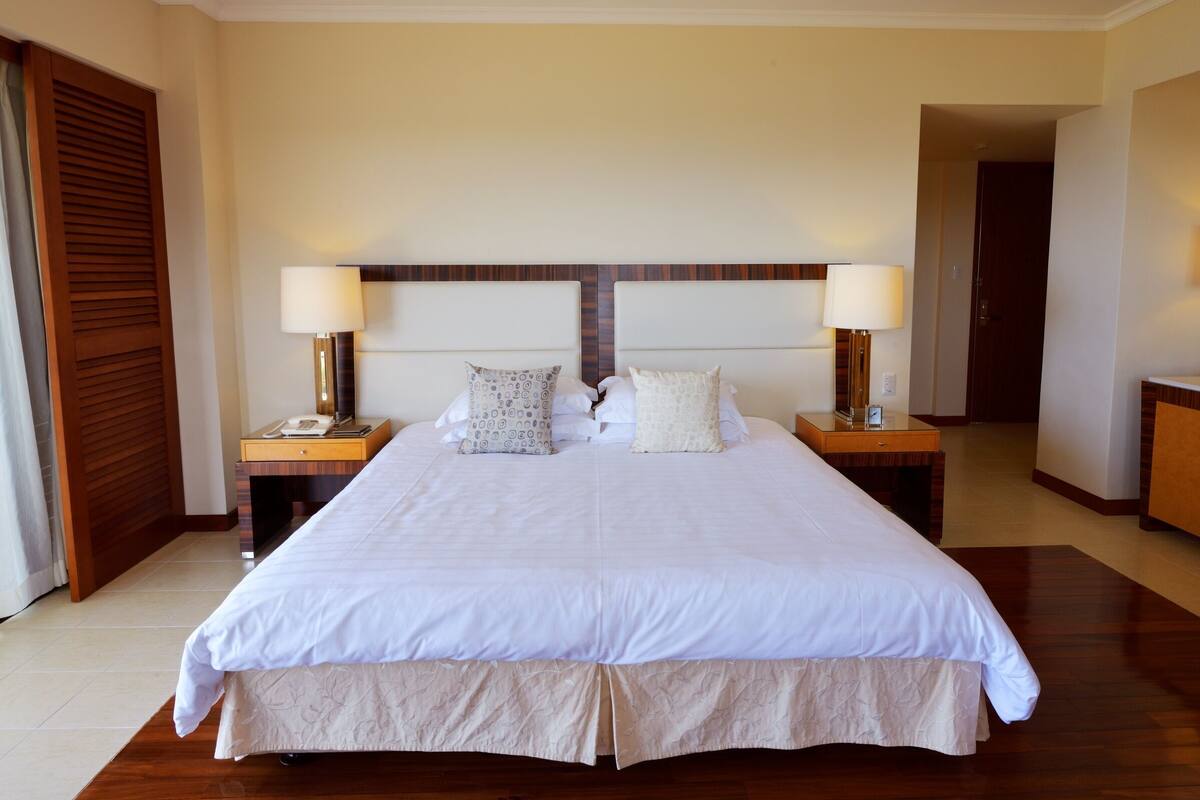 A double bed with a wooden headboard, two bedside tables with lamps, and a large mirror.