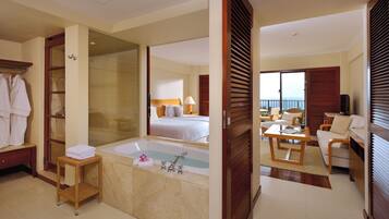 A hotel room with a large bathtub, a bed with two pillows, a desk with a chair, and a television.