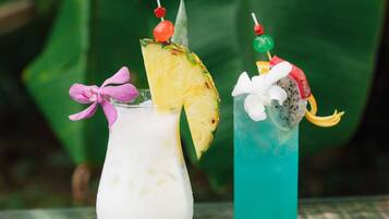 Two cocktails with tropical garnishes, one with a pineapple slice and the other with a dragon fruit.