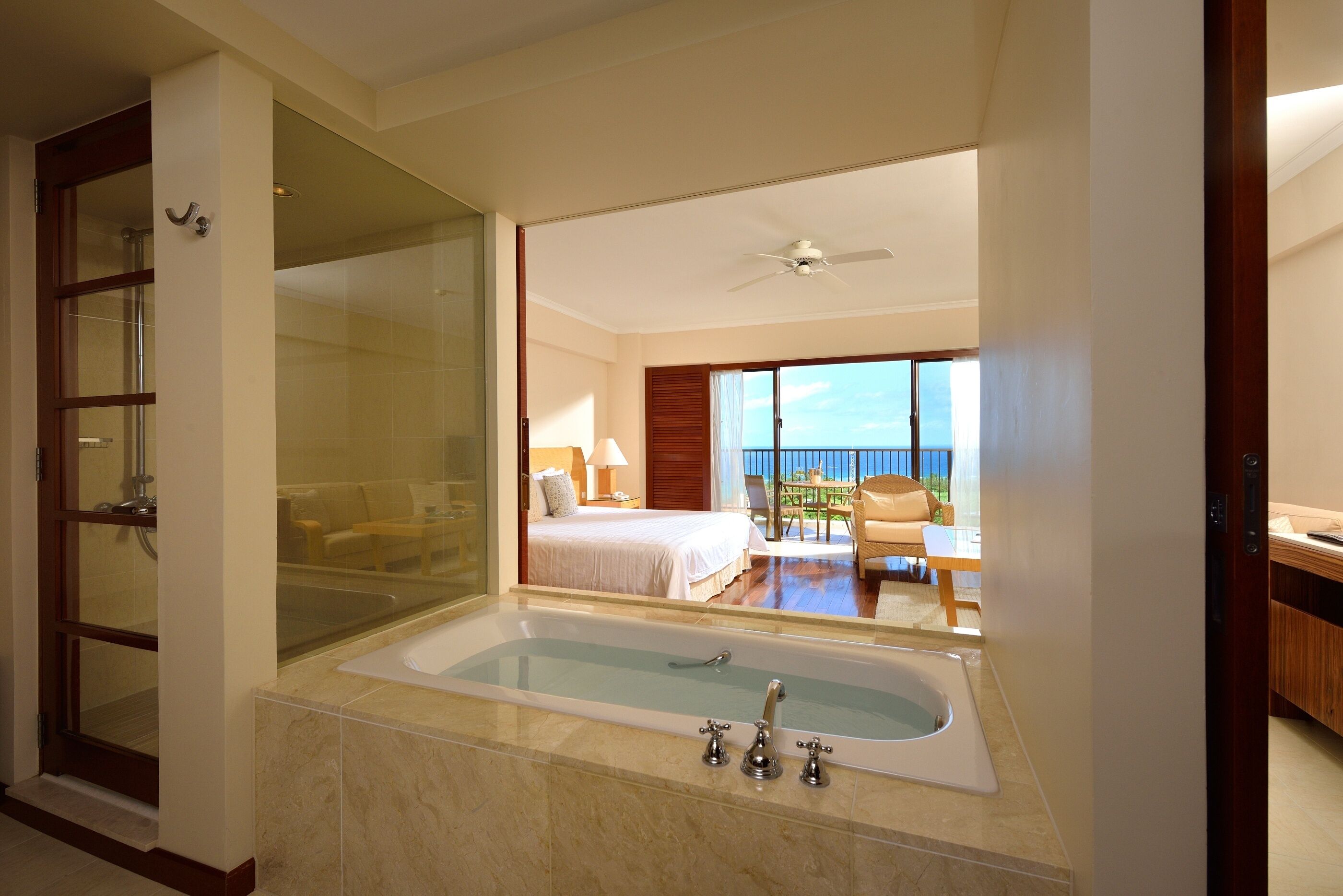 A hotel room with a large bathtub, a balcony with a view, and a separate shower area.