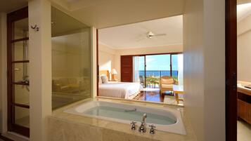 A hotel room with a large bathtub, a balcony with a view, and a separate shower area.