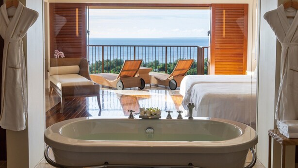 A hotel room with a large bathtub, two lounge chairs, a sofa, and a bed, with a view of the ocean. - The Atta Terrace Club Towers (Onna)