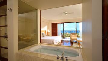A hotel bathroom with a large bathtub, a glass shower enclosure, and a balcony with a view.