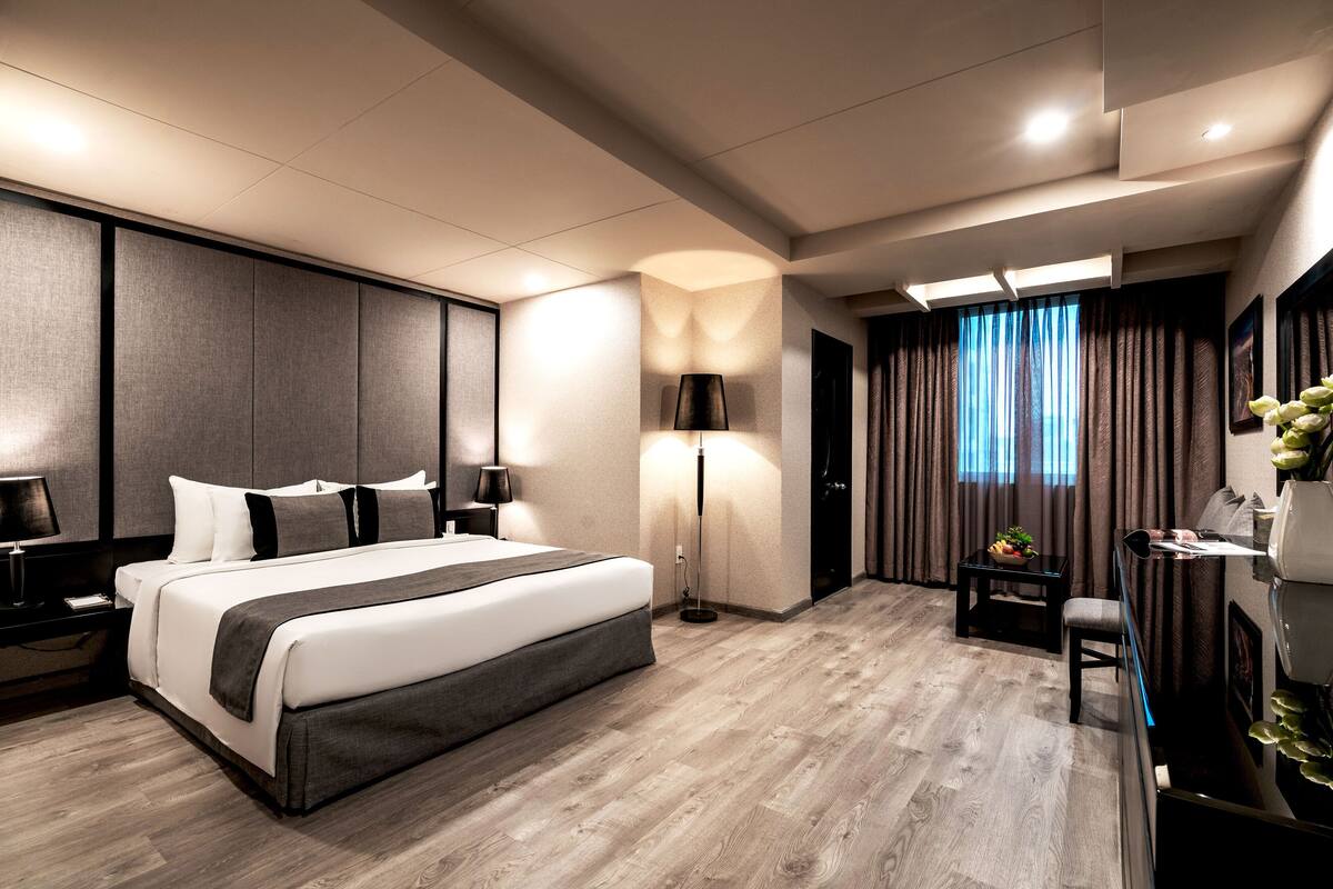 A modern hotel room with a large bed, bedside tables, a desk, and a chair.