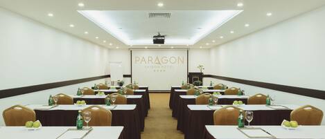 Una sala de conferencias en el Hotel Paragon Saigon, con mesas dispuestas para reuniones, equipada con sillas, botellas de agua y vasos.