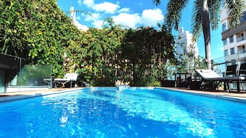 Una piscina al aire libre, sillones reclinables de piscina