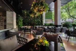 A modern outdoor seating area with wicker furniture, a green wall with plants, and a sign for PARAGON SAIGON HOTEL. - Paragon Saigon Hotel (Ho Chi Minh City)