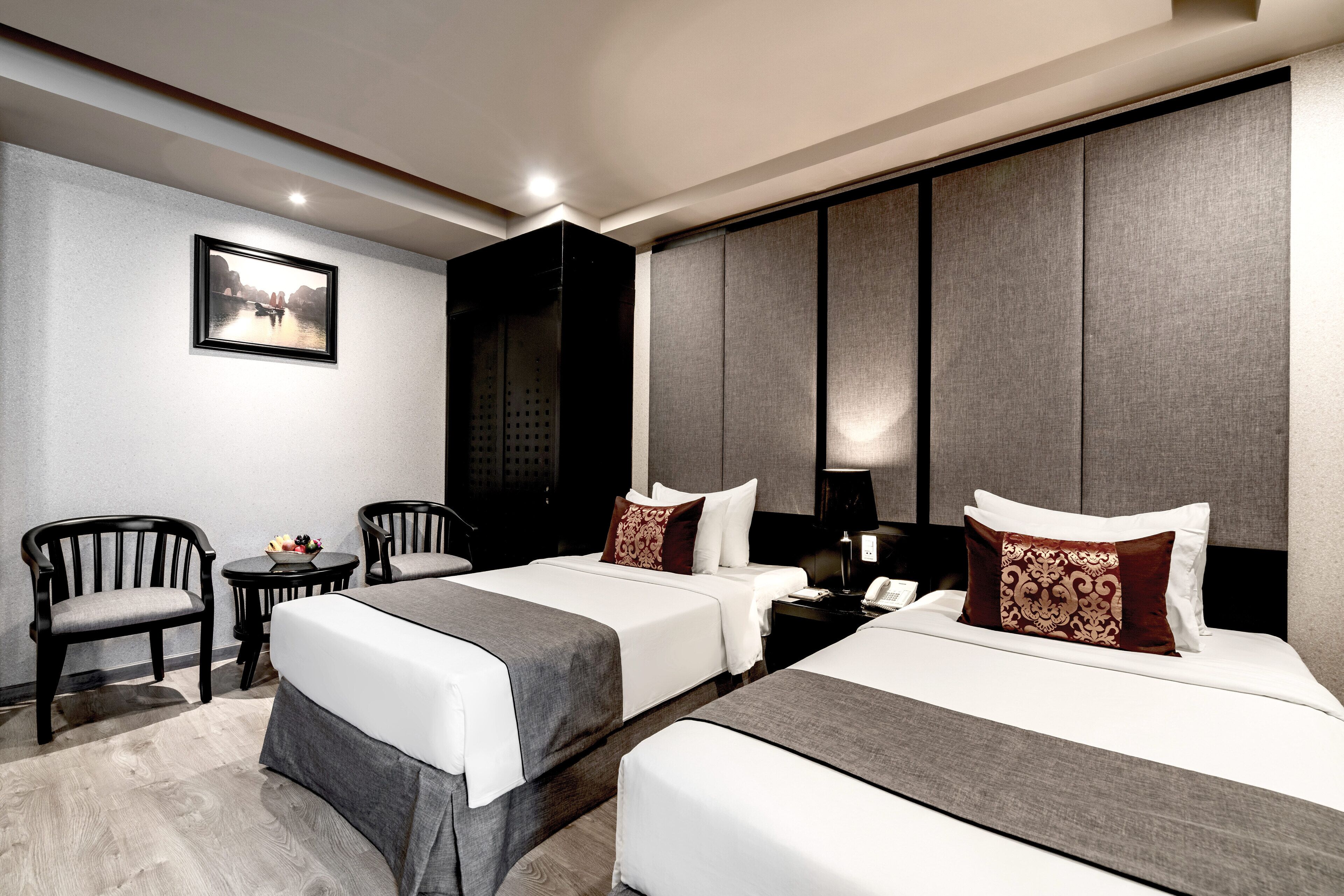 A hotel room with two beds, a desk, and two chairs.