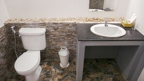 A bathroom with a toilet, sink, and a small trash bin.