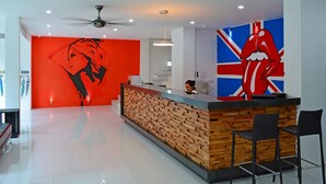 A modern reception area with a wooden reception desk, a large red and black mural, and a Union Jack design on the wall. - Art Hotel Chaweng Beach (Koh Samui)