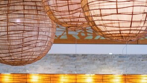 A reception area with a stone wall, a wooden reception desk, and a potted plant with orange flowers. - Chateau Royal Beach Resort and Spa (Nouméa)