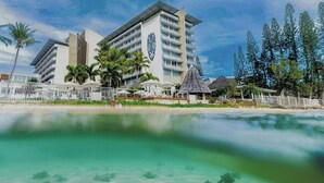 A resort hotel with a modern design, featuring multiple floors and a prominent logo on the facade. - Chateau Royal Beach Resort and Spa (Nouméa)