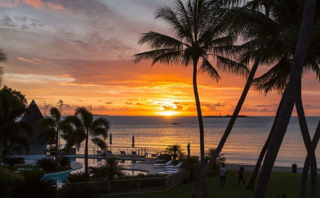 A resort with a pool, palm trees, and a sunset view.