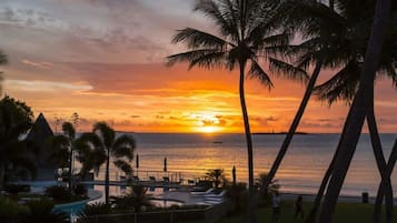 A resort with a pool, palm trees, and a sunset view.