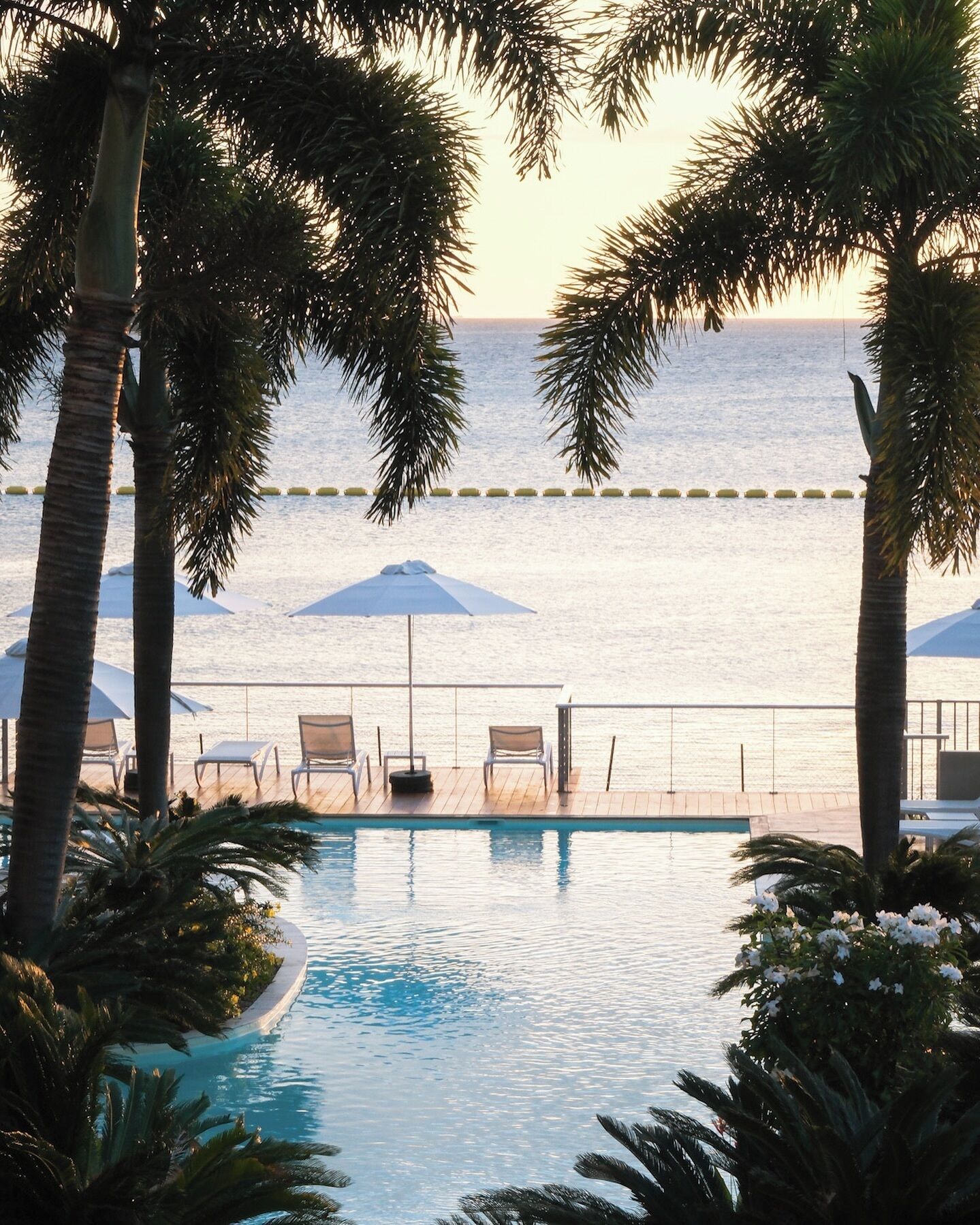 A pool area with lounge chairs and umbrellas, overlooking a body of water.