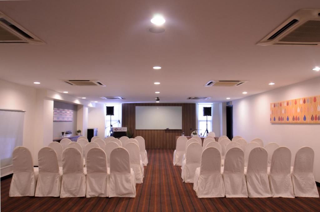 A conference room with rows of chairs, a projection screen, and a podium.