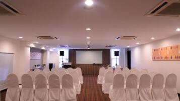 A conference room with rows of chairs, a projection screen, and a podium.