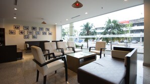 A hotel lobby with a reception desk, seating area, and large windows offering a view of the street and palm trees. - StarCity Hotel Alor Setar (Alor Setar)