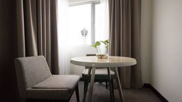 A room with a round table, a chair, and a window with curtains.