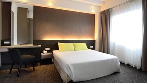 A hotel room with a large bed, a desk with a chair, a mirror, and a window with curtains. - StarCity Hotel Alor Setar (Alor Setar)