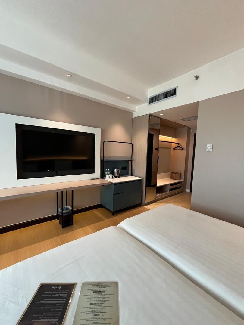 A hotel room with a bed, a desk, a TV, and a walk-in closet.