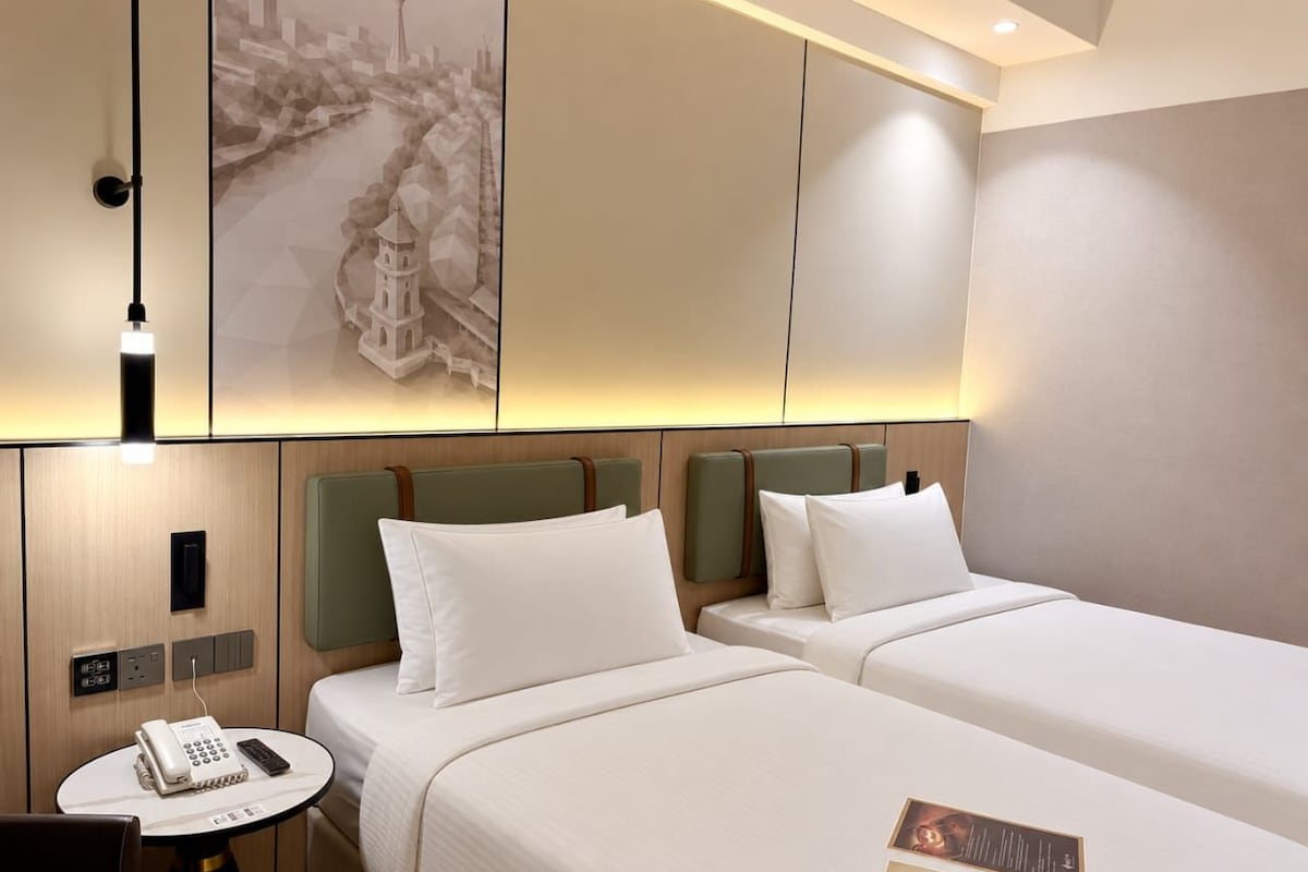 Ein Hotelzimmer mit zwei Betten, einem Nachttisch mit Telefon und einem Wandbild.