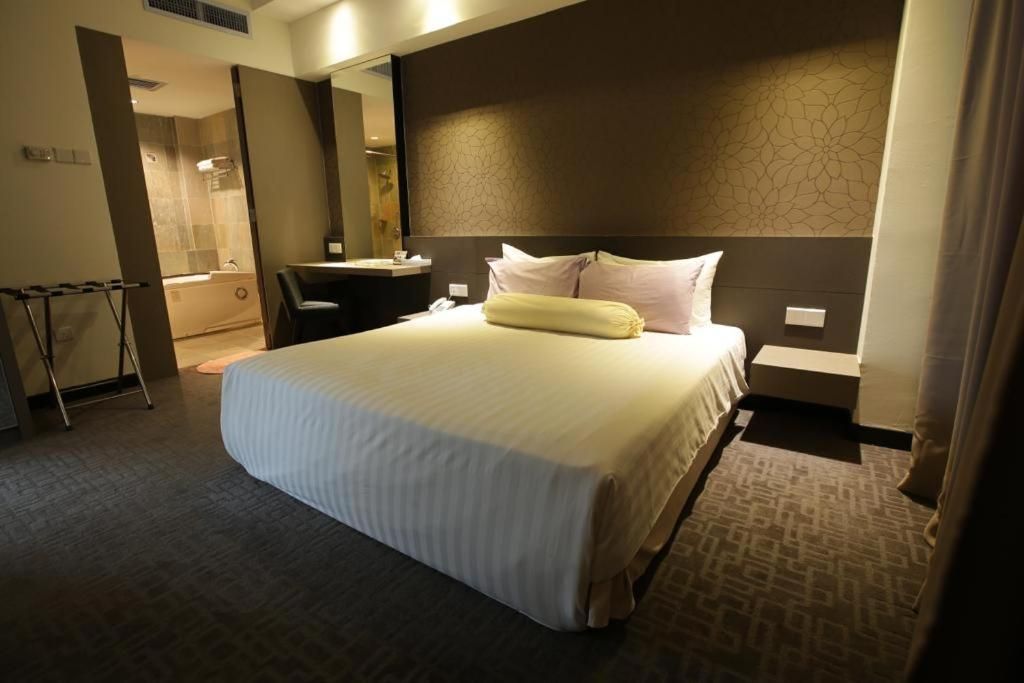 A hotel room with a large bed, a desk, a chair, and a bathroom visible through an open door.