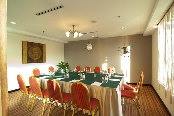 A conference room with a long table, red chairs, a chandelier, and a clock on the wall.