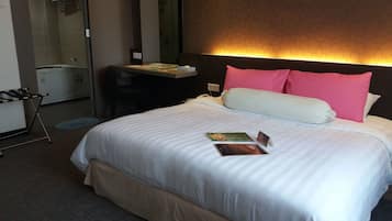 Una camera d'albergo con un letto grande, un comodino, uno specchio e una scrivania con una sedia.