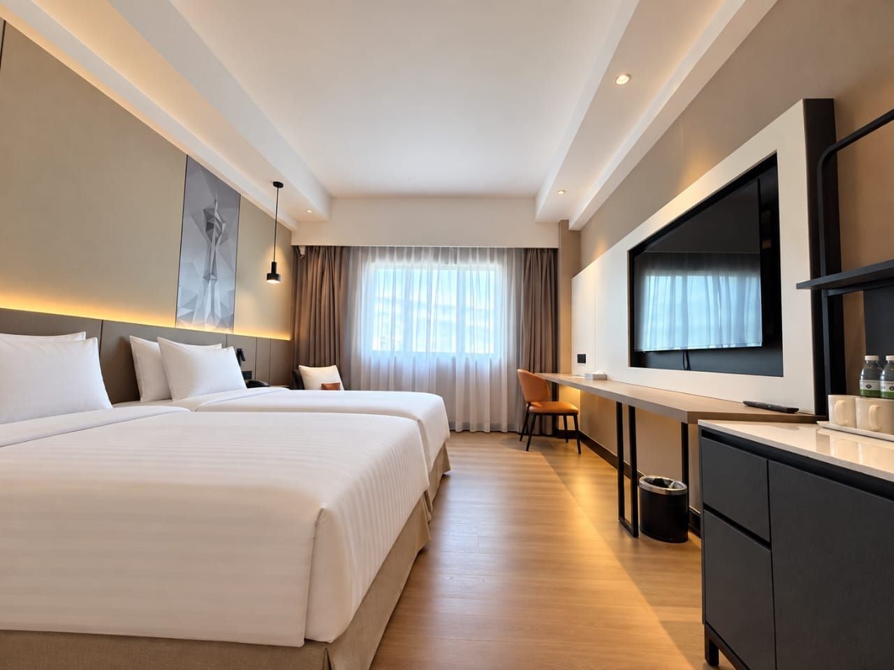 A hotel room with two beds, a desk, a TV, and a large window with curtains.