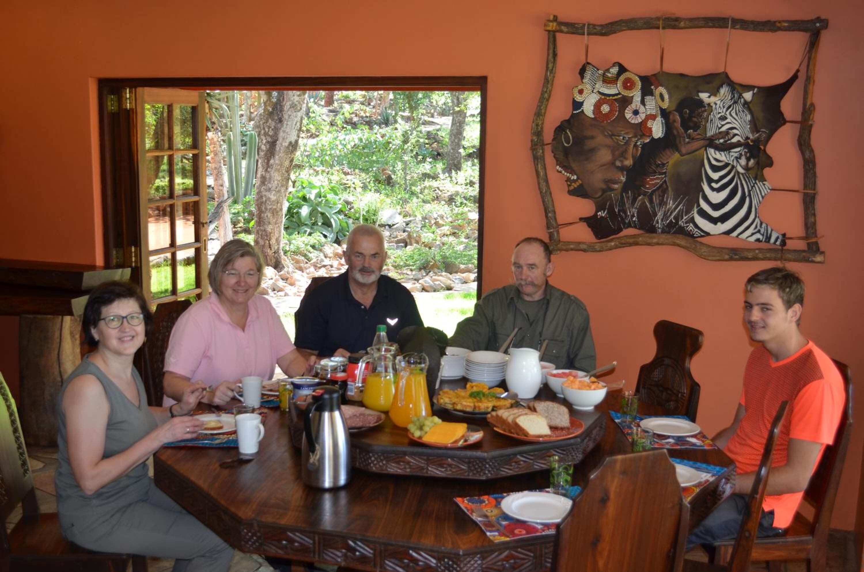 A group of people seated at a wooden dining table with a variety of breakfast items.