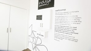 Ein Flur mit einem Schild für Indulge Apartments, einer Willkommensbotschaft und einem Schlüsseldepot.