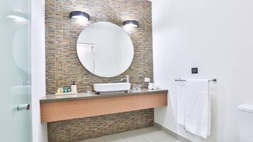 A modern bathroom with a large mirror, two wall-mounted lights, a sink, and a toilet.