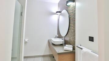 A modern bathroom with a white sink, a large mirror, and a towel rack.