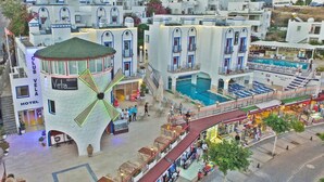 Un hotel con un molino, una piscina y una zona comercial.