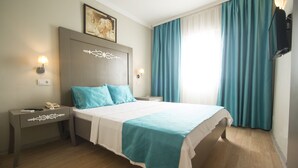 Habitación de hotel ordenada con cama, mesitas de noche, lámpara de pared y un cuadro.