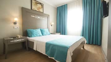 Quarto de hotel bem organizado com cama, mesas de cabeceira, luminária na parede e um quadro.