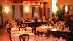 Comedor con varias mesas dispuestas para una comida, con platos, vasos y cubiertos ordenados.
